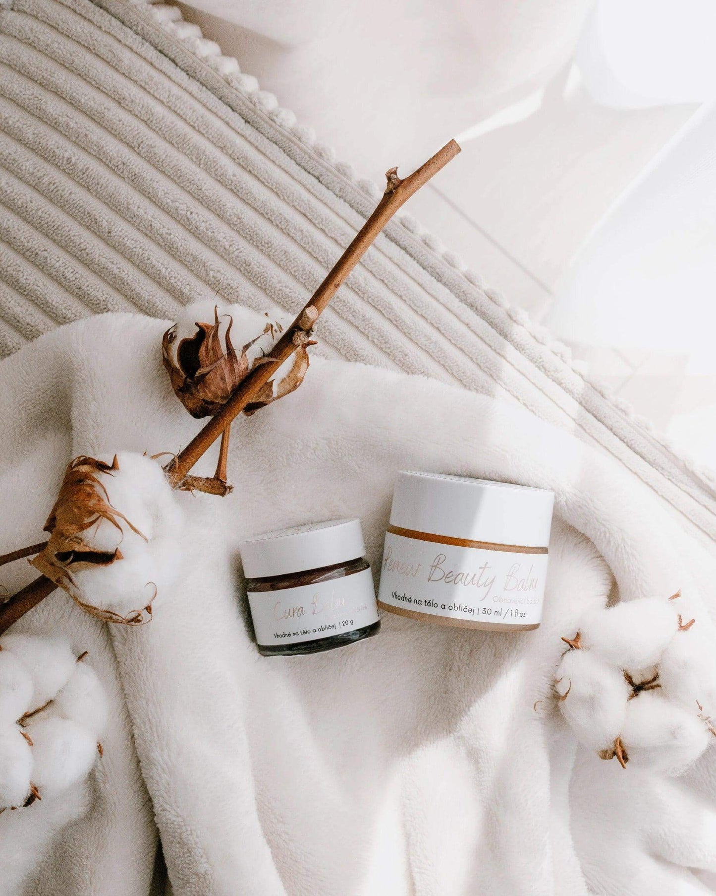 Přírodní balzámy Cura Balm od Protože Jsi na jemném bílém ručníku s bavlnou.