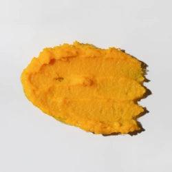 Rozetřená textura hydratačního másla s ovesnými vločkami, ideální pro citlivou pokožku a atopickou dermatitidu.